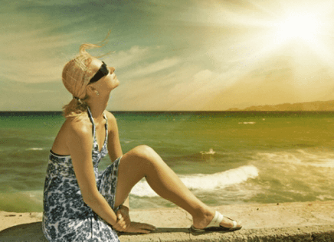 Woman relaxing on beach wearing sunglasses
